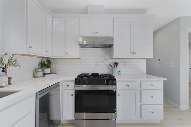 kitchen featuring tasteful backsplash, white cabinetry, exhaust hood, stainless steel gas range oven, and light stone countertops