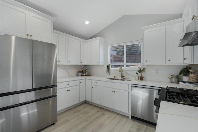 kitchen with vaulted ceiling, sink, white cabinets, stainless steel appliances, and light stone countertops