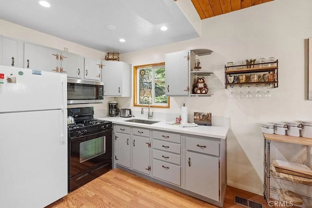 kitchen with gas stove, sink, light hardwood / wood-style flooring, white fridge, and wood ceiling