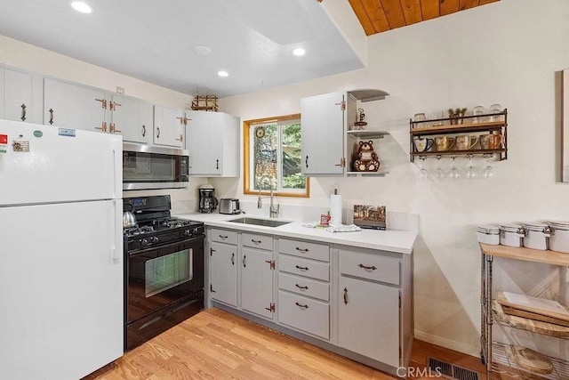 43869 Mendocino Dr, Big Bear Lake, CA 92315 - kitchen with freestanding refrigerator, stainless steel microwave, black gas stove, a sink, and light wood-type flooring