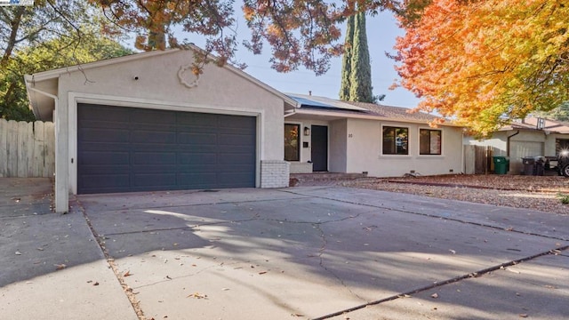 ranch-style home featuring a garage and solar panels