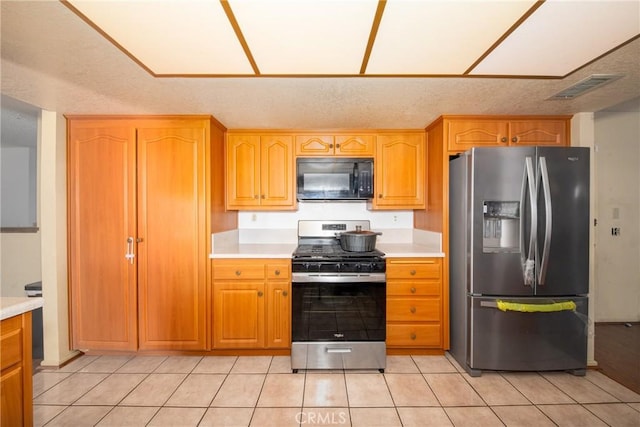 kitchen with light tile patterned floors, a textured ceiling, and appliances with stainless steel finishes