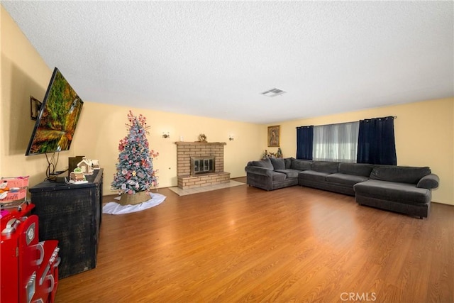 living room featuring a brick fireplace, a textured ceiling, and hardwood / wood-style flooring