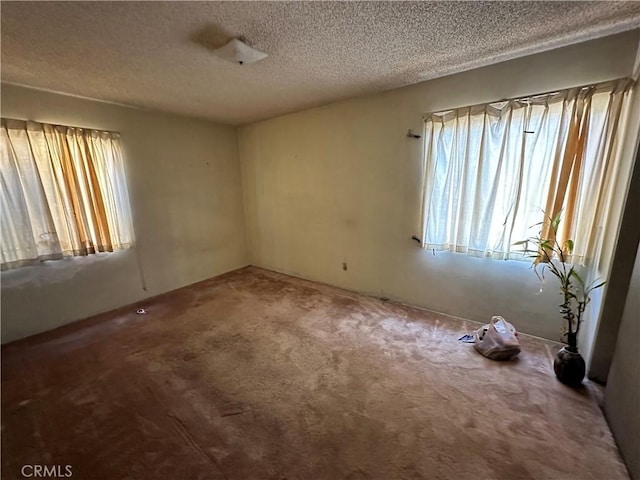 carpeted empty room featuring a textured ceiling