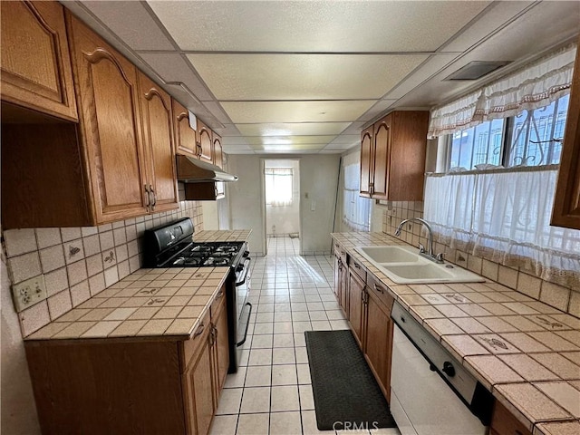 kitchen featuring tile countertops, dishwasher, backsplash, sink, and black range with gas cooktop