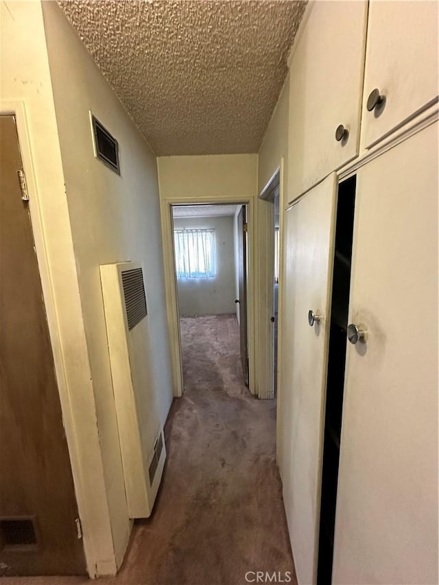 hall with carpet and a textured ceiling