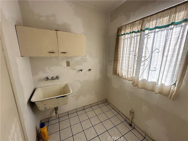 clothes washing area featuring light tile patterned floors and sink