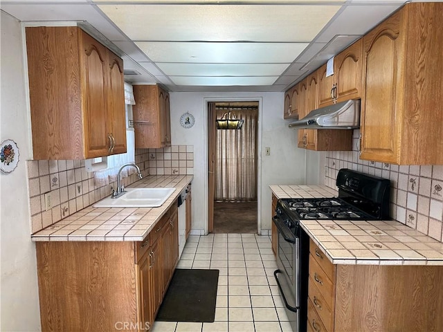 kitchen featuring light tile patterned flooring, black gas range, tile countertops, and sink