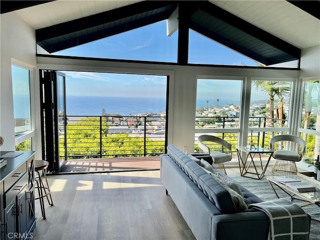 sunroom featuring vaulted ceiling with beams, a wealth of natural light, and a water view