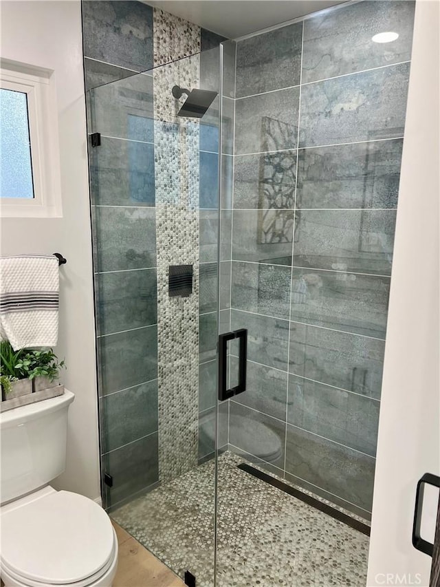 bathroom featuring hardwood / wood-style floors, toilet, and an enclosed shower