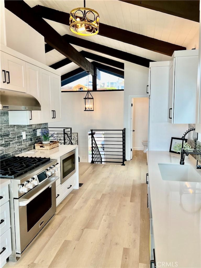 kitchen featuring decorative backsplash, appliances with stainless steel finishes, sink, white cabinets, and vaulted ceiling with beams