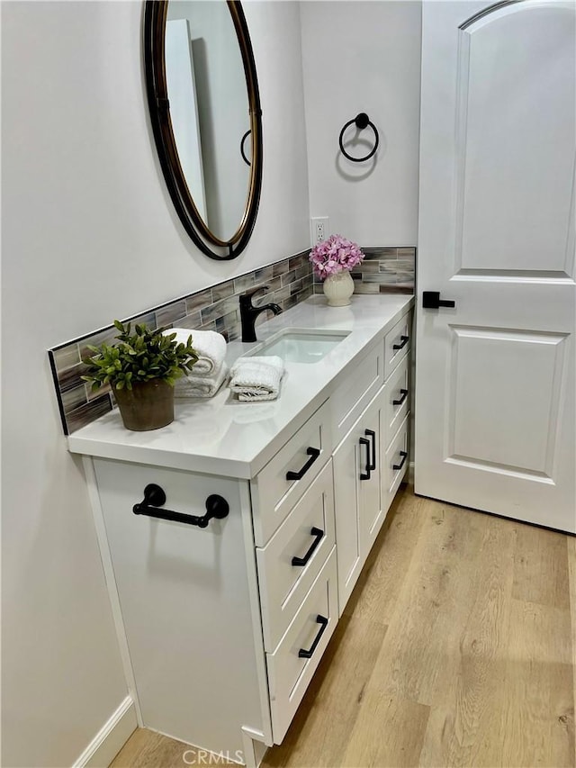 bathroom with vanity, hardwood / wood-style flooring, and backsplash