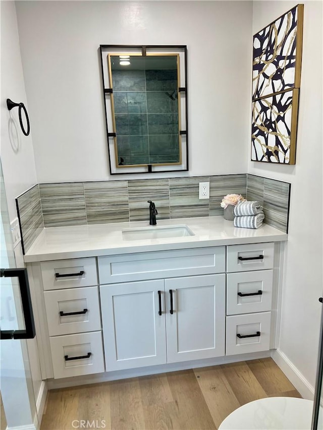 bathroom with decorative backsplash, wood-type flooring, and vanity