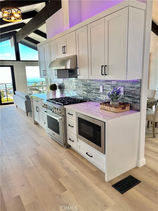 kitchen with tasteful backsplash, stainless steel appliances, beam ceiling, light hardwood / wood-style floors, and white cabinetry