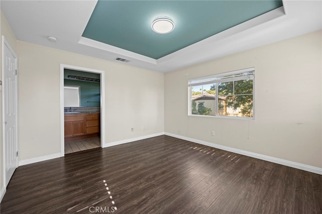 unfurnished room with dark wood-type flooring, sink, and a raised ceiling