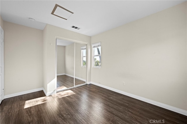 unfurnished bedroom featuring a closet and dark hardwood / wood-style flooring