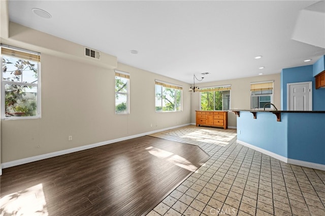 unfurnished living room featuring a notable chandelier and light hardwood / wood-style flooring