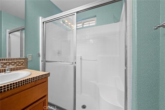 bathroom featuring a shower with shower door, decorative backsplash, and vanity