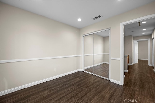 unfurnished bedroom featuring a closet and dark hardwood / wood-style flooring