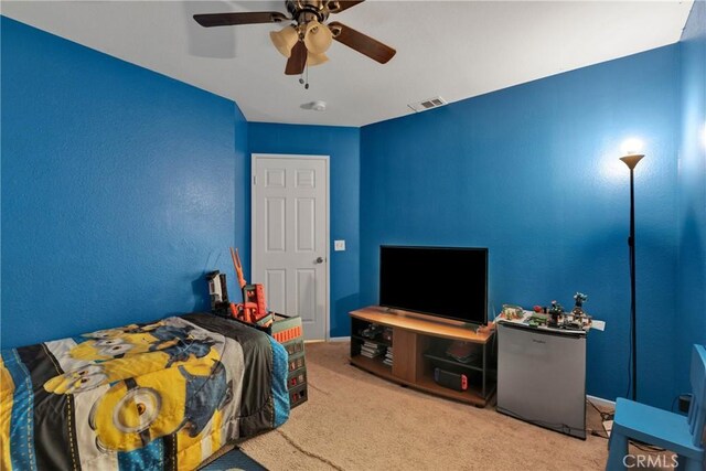 carpeted bedroom featuring ceiling fan and stainless steel refrigerator