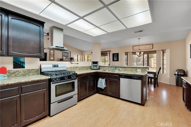 kitchen with kitchen peninsula, appliances with stainless steel finishes, island range hood, sink, and light hardwood / wood-style flooring