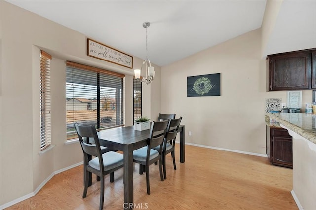 dining room with light hardwood / wood-style floors, lofted ceiling, and a notable chandelier