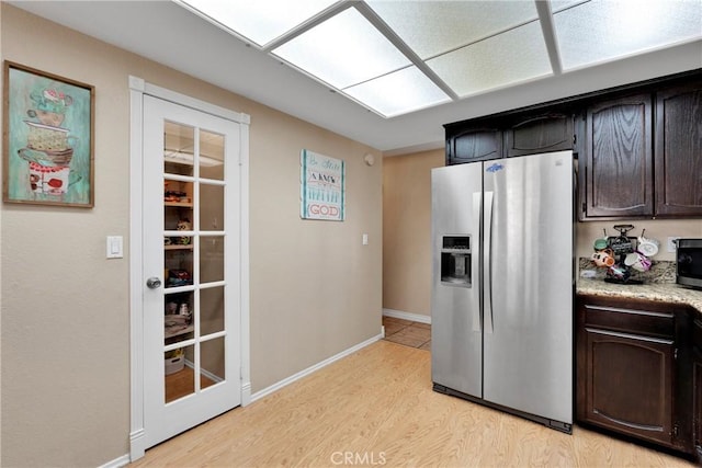 kitchen with appliances with stainless steel finishes, dark brown cabinetry, and light hardwood / wood-style flooring