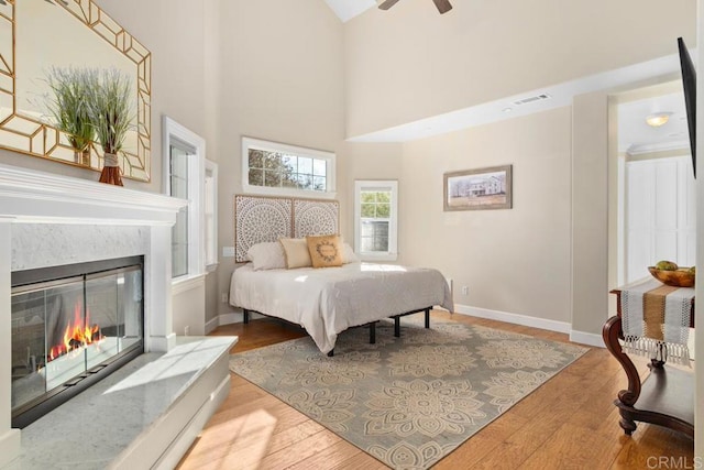 bedroom with hardwood / wood-style floors, ceiling fan, and a high ceiling