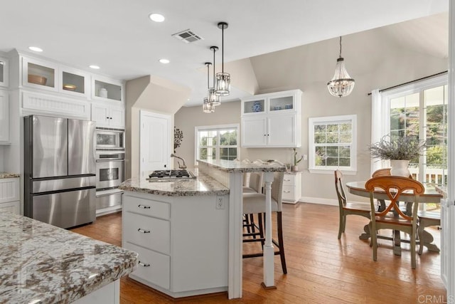 kitchen with appliances with stainless steel finishes, pendant lighting, a center island with sink, white cabinetry, and lofted ceiling