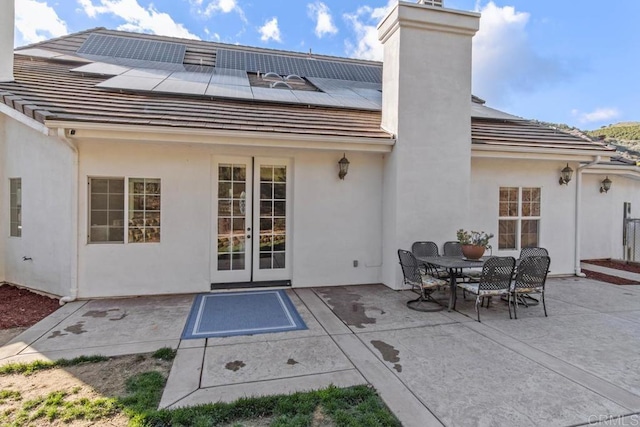 back of property with french doors, solar panels, and a patio area