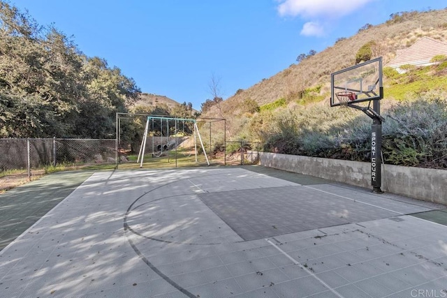 view of basketball court with a mountain view and a playground