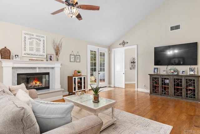 living room featuring ceiling fan, light hardwood / wood-style floors, high vaulted ceiling, and french doors