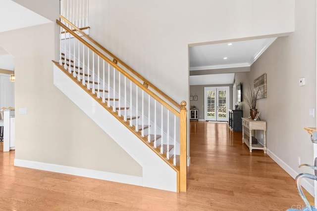 staircase featuring hardwood / wood-style floors, crown molding, and french doors