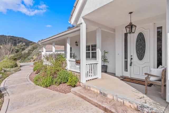 view of exterior entry featuring a mountain view and covered porch