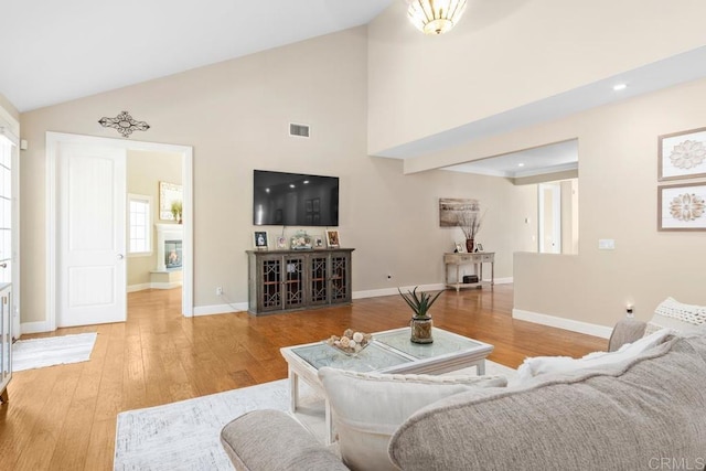 living room featuring light wood-type flooring and high vaulted ceiling