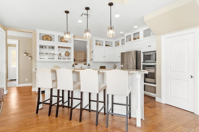 kitchen with white cabinetry, light stone countertops, light hardwood / wood-style flooring, and appliances with stainless steel finishes