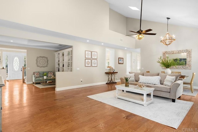 living room featuring wood-type flooring, ceiling fan with notable chandelier, and ornamental molding