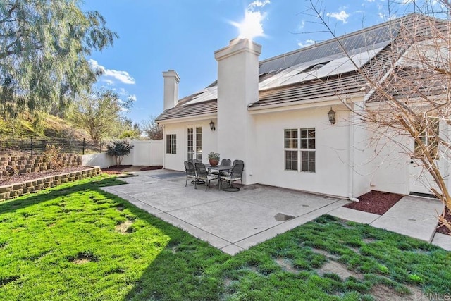 back of house featuring solar panels, a patio, and a yard