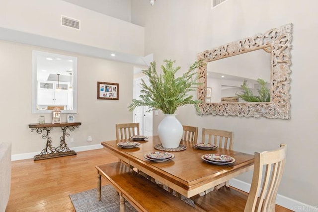 dining space with a towering ceiling and hardwood / wood-style flooring