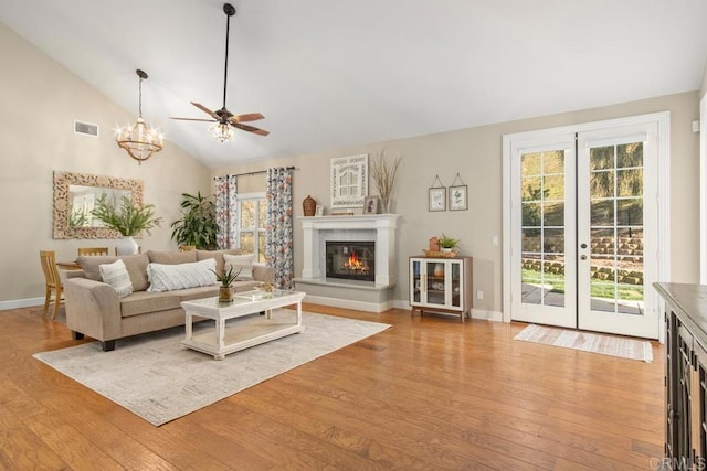 living room with french doors, ceiling fan with notable chandelier, light hardwood / wood-style flooring, and lofted ceiling