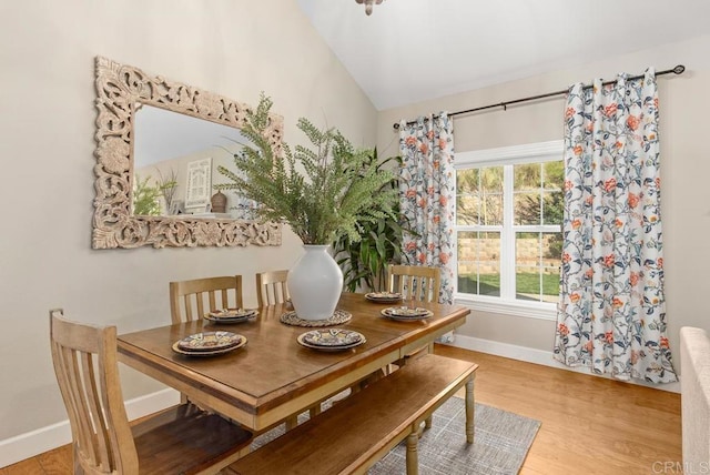 dining area with wood-type flooring and vaulted ceiling