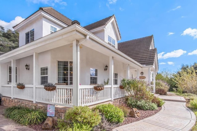 view of property exterior with covered porch and stucco siding