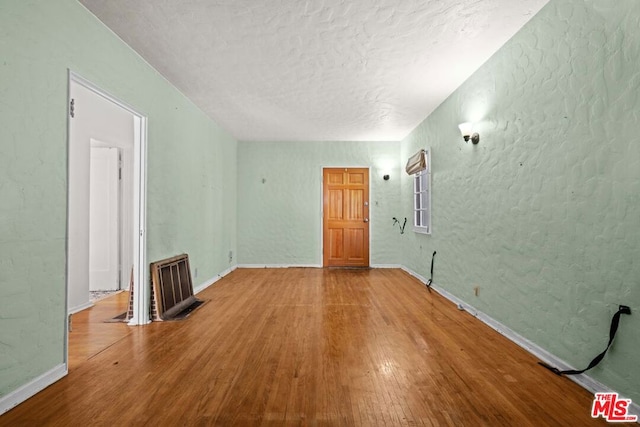 unfurnished room with hardwood / wood-style floors and a textured ceiling