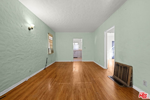 unfurnished living room featuring hardwood / wood-style floors, a textured ceiling, and heating unit