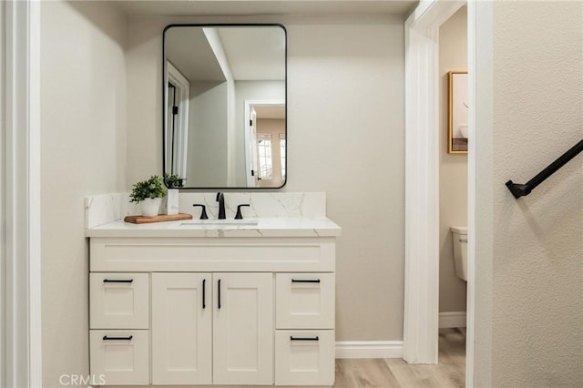 bathroom featuring vanity, wood-type flooring, and toilet