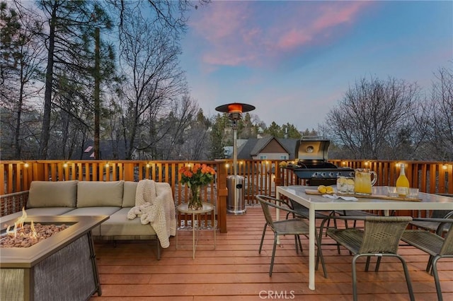 deck at dusk with an outdoor living space with a fire pit