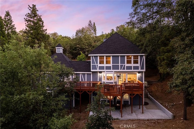 back house at dusk featuring a patio area and a wooden deck