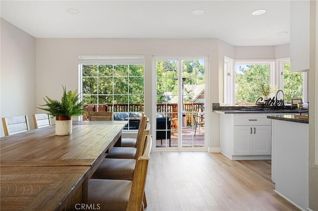 unfurnished dining area with a wealth of natural light, sink, and light wood-type flooring