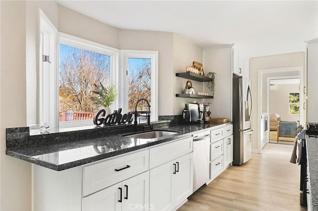 kitchen with white cabinets, stainless steel appliances, light hardwood / wood-style floors, and sink