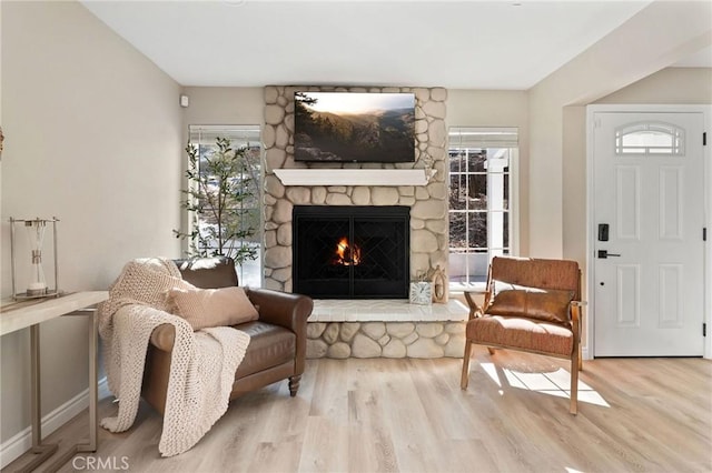 living area with a stone fireplace and light hardwood / wood-style floors